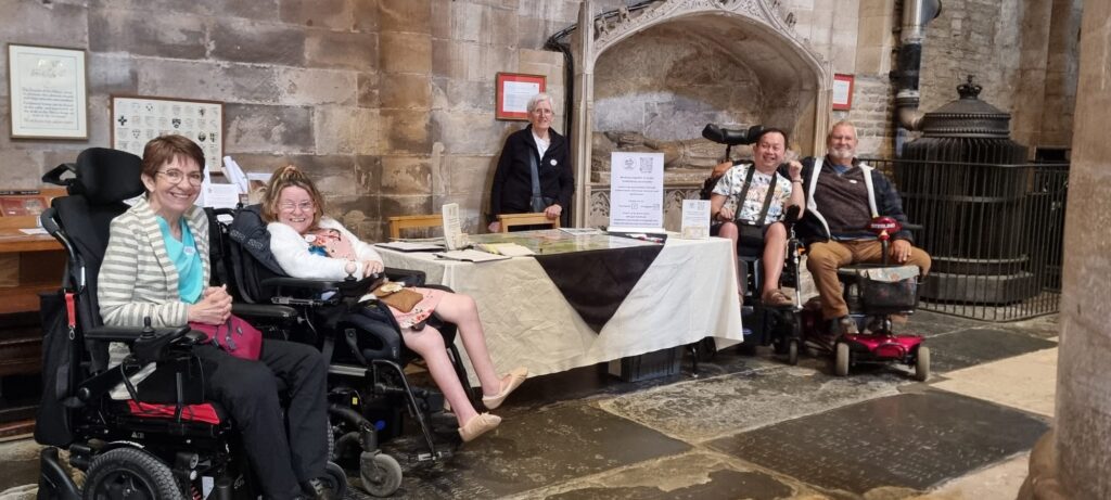 A group of four people sat next to a stall with information about the access forum